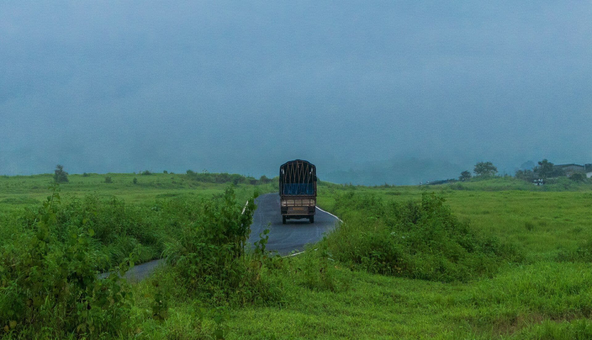 A goods truck on a winding road through green monsoon fields